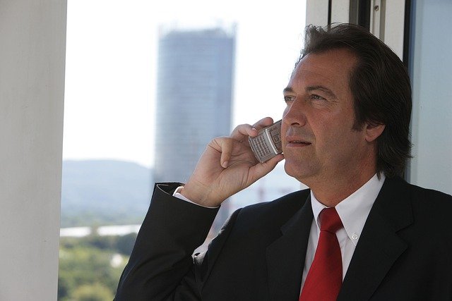business man standing by window talking on cell phone